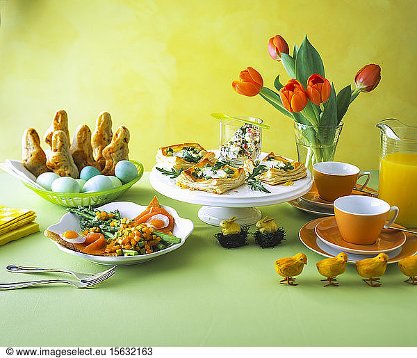 Zu Ostern auf dem Tisch vor der gelben Wand arrangierte Speisen