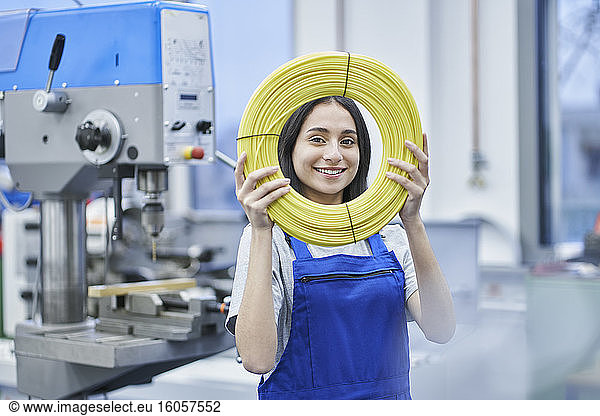 Zufriedene Arbeiterin  die in einer Fabrik aufgerollte Kabel durchsieht