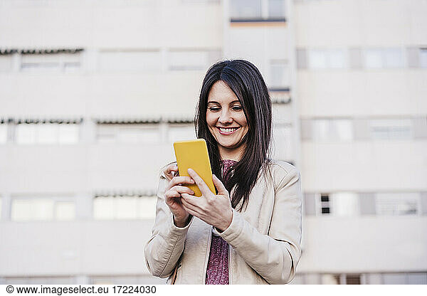 Zufriedene Frau  die lächelnd ein Mobiltelefon benutzt
