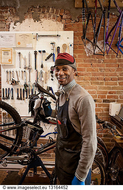 Zufriedener Mechaniker  der ein Fahrrad hochhält