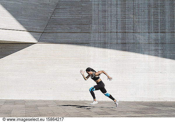 Zurückgezogene Ansicht einer Athletin  die auf Beton vertikal läuft