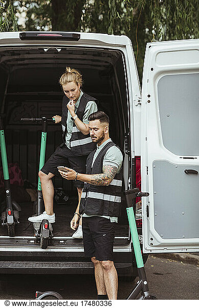 Zusteller teilt Smartphone mit Mitarbeiterin im Lieferwagen