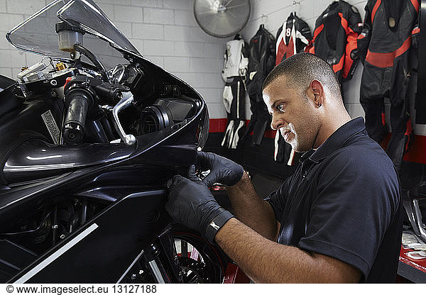 Zuversichtlicher Arbeiter untersucht Motorrad in Werkstatt