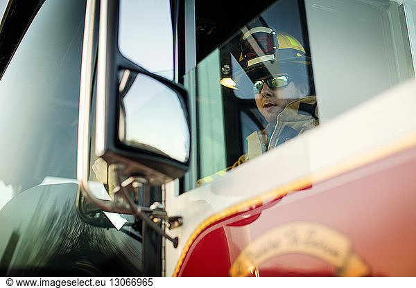 Zuversichtlicher Feuerwehrmann im Feuerwehrauto sitzend