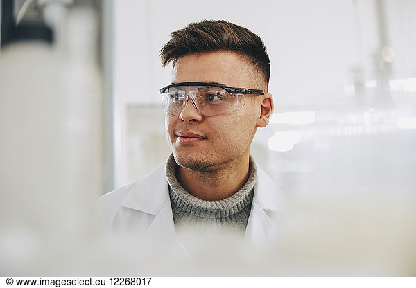 Zuversichtlicher junger Chemiestudent mit Brille im Labor