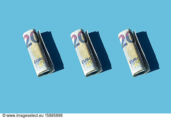 Zwanzig gerollte Euro-Banknoten auf blauem Hintergrund