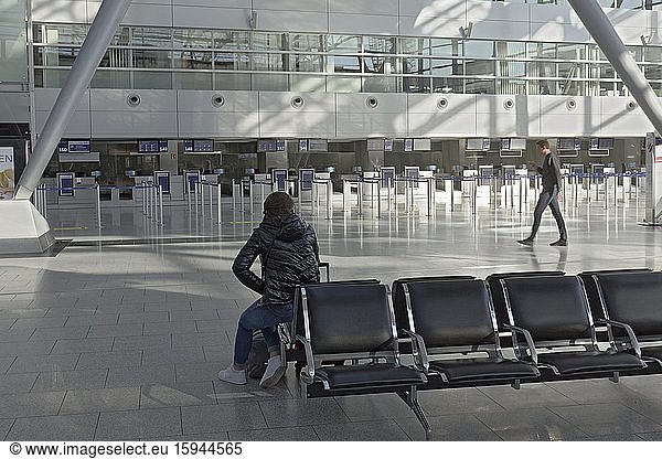 Zwei einzelne Personen in der leeren Abflughalle  Flughafen Düsseldorf während der Corona-Pandemie  Nordrhein-Westfalen  Deutschland  Europa