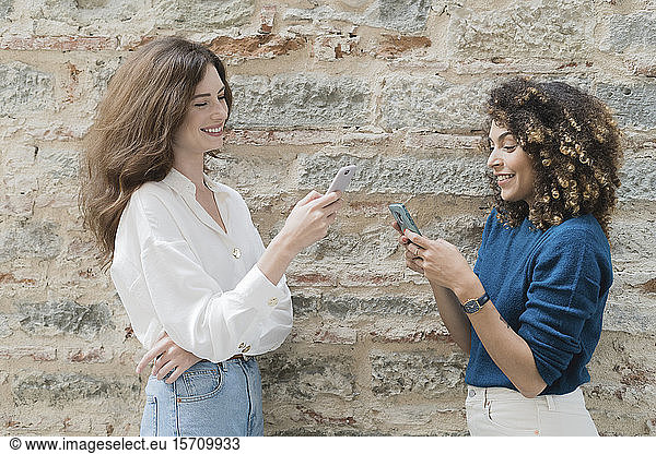 Zwei Frauen benutzen Smartphones im Freien