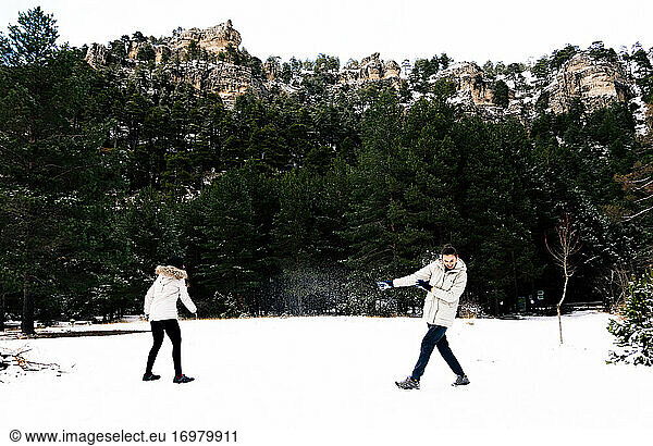 Zwei Frauen  die sich in einer natürlichen Schneelandschaft mit Schneebällen bewerfen.