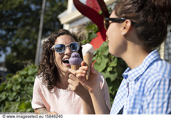 Zwei Frauen essen Eiswaffeln in der Sonne.