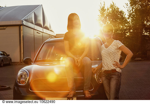 Zwei Frauen vor ihrem Auto bei Gegenlicht