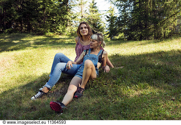 Zwei Freundinnen auf einer Waldlichtung liegend  Sattelbergalm  Tirol  Österreich