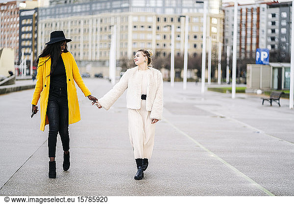Zwei Freundinnen gehen Hand in Hand in der Stadt