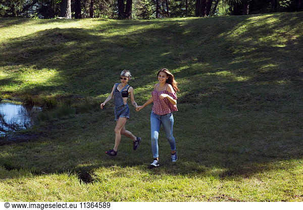 Zwei Freundinnen laufen auf einer Waldlichtung  Sattelbergalm  Tirol  Österreich