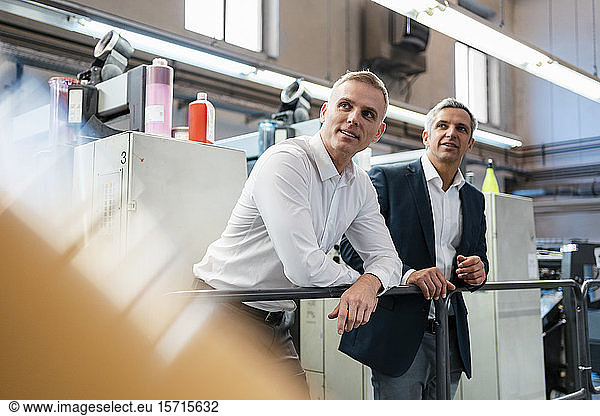 Zwei Geschäftsleute in einer Druckerei  die sich umsehen