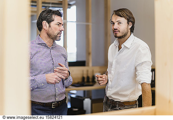 Zwei Geschäftsleute unterhalten sich im hölzernen Großraumbüro
