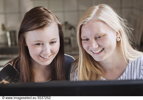 Zwei glückliche Freunde lächeln beim Anblick des Computers