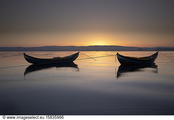 zwei Holzboote bei Sonnenaufgang