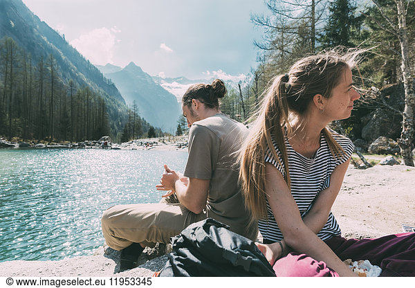 Zwei junge erwachsene Wanderer sitzen am Bergsee  Lombardei  Italien