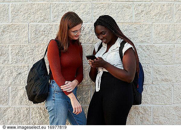 Zwei junge Frauen schauen auf ihr Smartphone. Multiethnisches Konzept