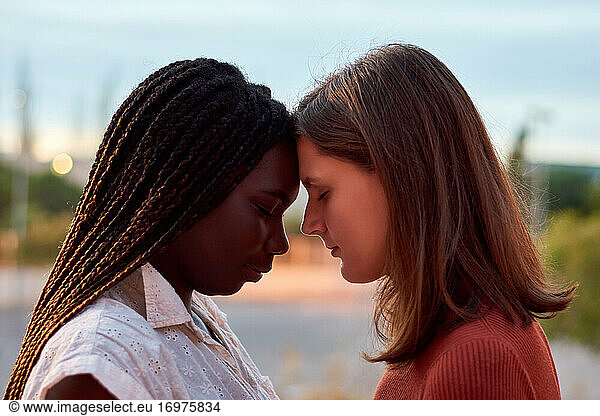 Zwei junge Frauen umarmen sich ernsthaft. Multiethnisches Konzept
