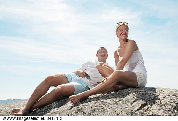 Zwei junge Leute sitzen am Strand.