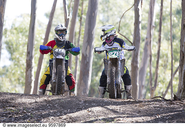 Zwei junge männliche Motocross-Fahrer im Wald im Gespräch