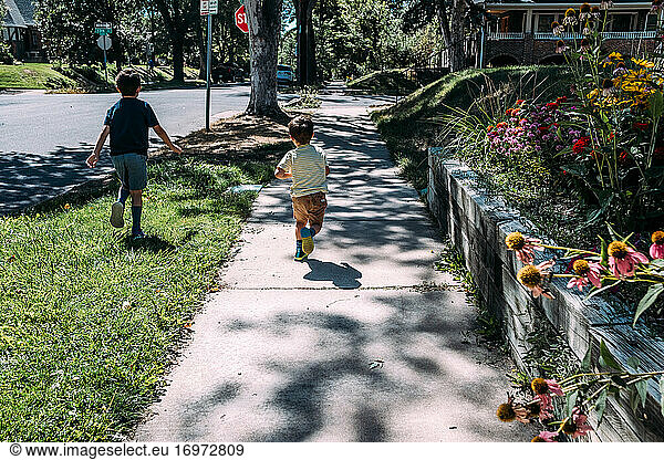 Zwei Jungen laufen auf einem Bürgersteig in der Nachbarschaft