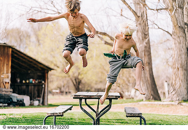 Zwei Jungen springen vom Picknicktisch