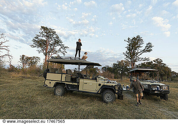 Zwei Kinder auf dem Dach eines Safarifahrzeugs bei einer Pirschfahrt zum Sonnenaufgang