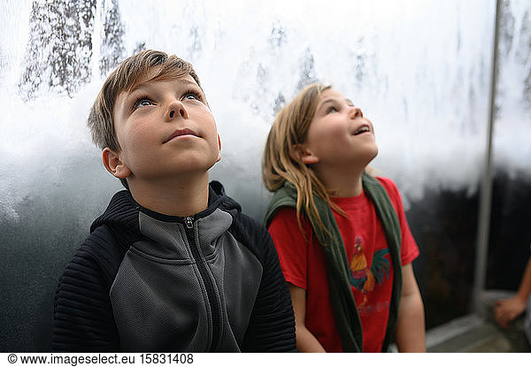 Zwei Kinder schauen staunend zu Wellen und Wasser auf