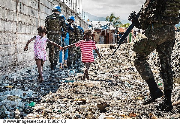 Zwei Kinder und UN-Patrouille  blaue Helme  gehen durch Müll  Cité Soleil  Port-au-Prince  Ouest  Haiti  Mittelamerika