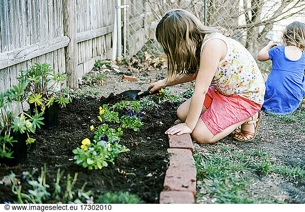 Zwei kleine Mädchen kümmern sich um ihr kleines Gartenbeet im Garten