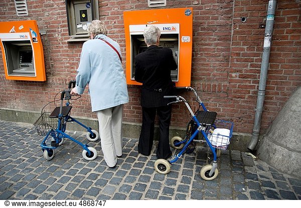 Zwei ältere Frauen ziehen Bargeld von einem Geldautomaten ab.