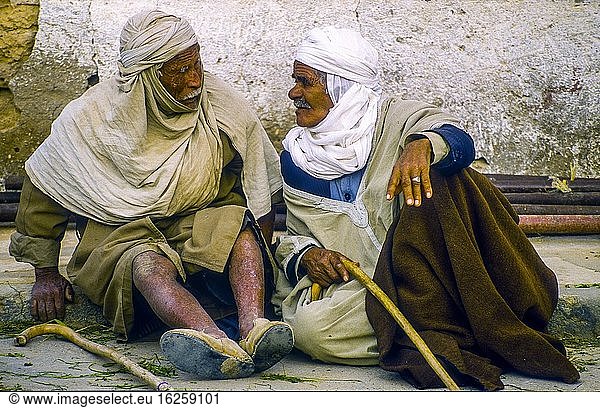 Zwei ältere Männer unterhalten sich in einer ruhigen Straße von Douz  Tunesien  einer Oasenstadt am Rande der Sahara  in der Datteln angebaut werden.