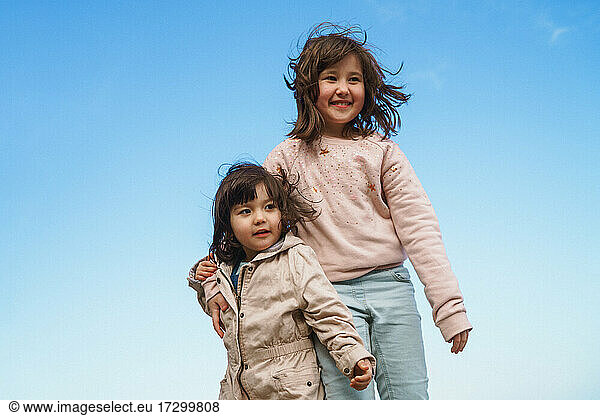 zwei Mädchen gegen blauen Himmel
