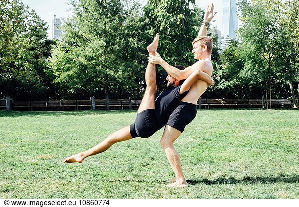 Zwei Männer üben Yoga-Lift-Position im Park
