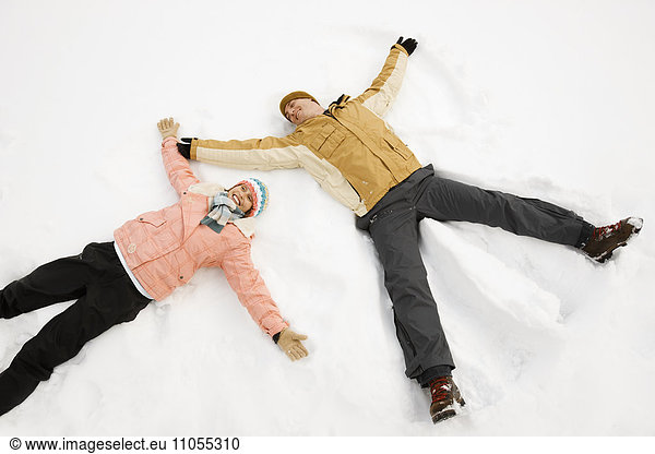 Zwei Menschen  ein Mann und eine Frau  die im Schnee liegen  bilden Schnee-Engelformen.