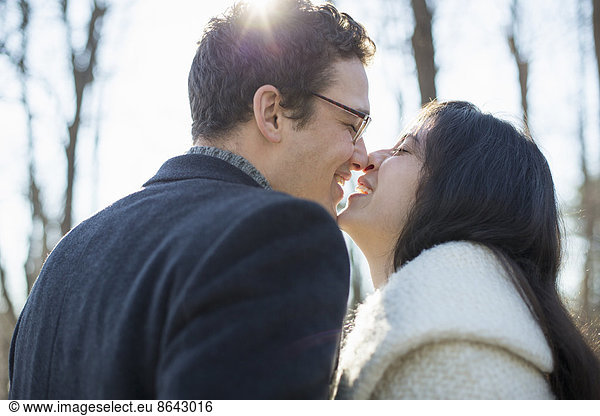 Zwei Menschen  ein Paar  ein Mann und eine Frau an einem Wintertag im Wald. Sie küssen sich.