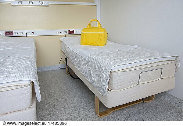 Zwei Patientenbetten in einer Entbindungsstation  eine leuchtend gelbe Tasche.