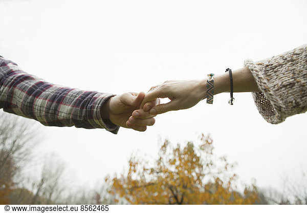 Zwei Personen halten sich an den Händen  ein Paar im Freien.