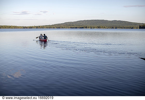 Zwei Personen paddeln in einem Kanu auf einem See in Maine in die Ferne