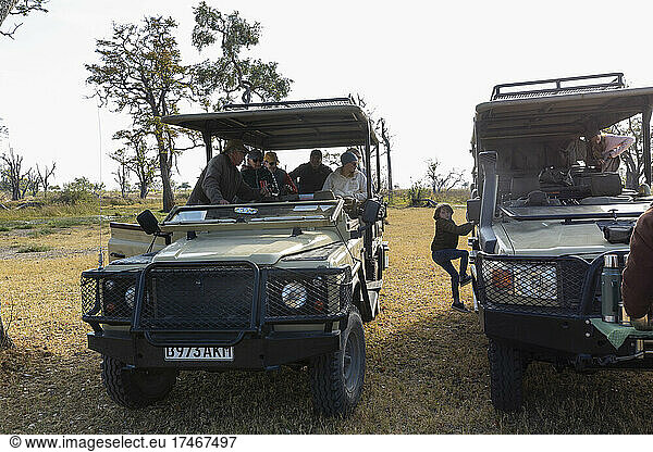 Zwei Safarifahrzeuge nebeneinander  ein Junge klettert von einem zum anderen