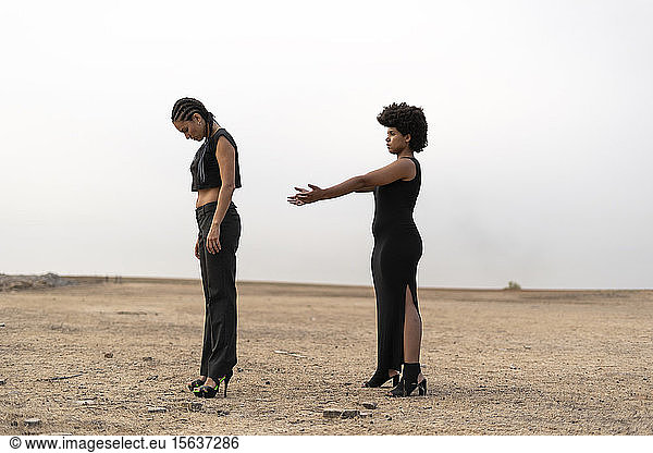 Zwei schwarz gekleidete Frauen stehen in trostloser Landschaft