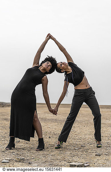 Zwei schwarz gekleidete Frauen treten in trostloser Landschaft auf