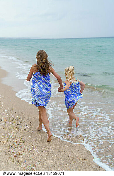 Zwei Schwestern beim Laufen am Strand.