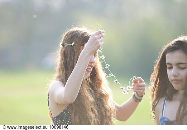 Zwei Teenager-Mädchen  die sich im Park Kopfbedeckungen anziehen.