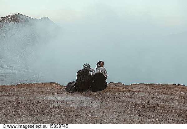 Zwei Wanderer sitzen und schauen auf den Ijen-See