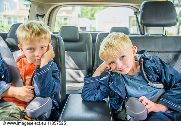 Zwillingsbrüder sitzen hinten im Fahrzeug  gelangweilte Mienen