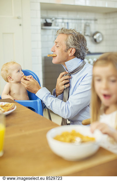 Father and children eating breakfast in kitchen